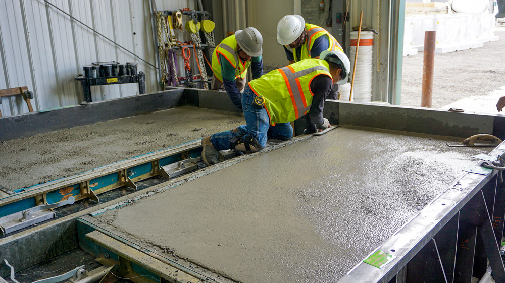 Peaks Precast team finishing a concrete panel surface inside the controlled manufacturing facility