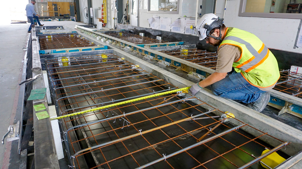 Engineer measuring rebar layout precision inside the Fast Foundations production facility, Buena Vista Colorado